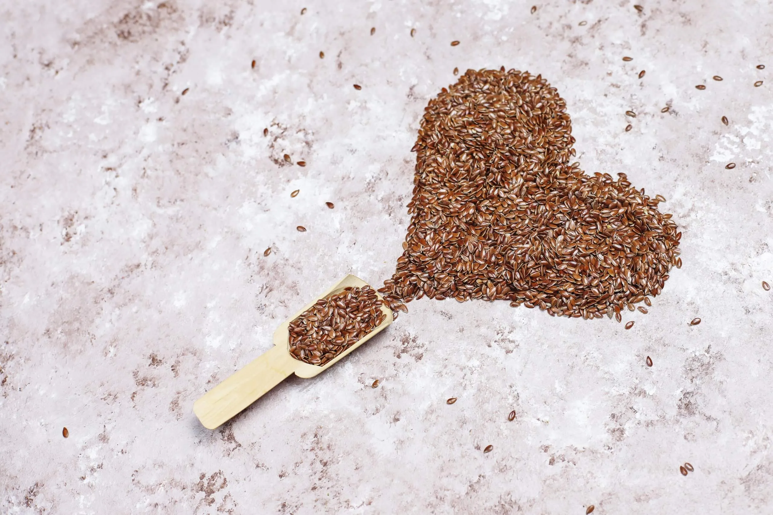 Heart shaped flax seeds concrete background with space copy top view scaled
